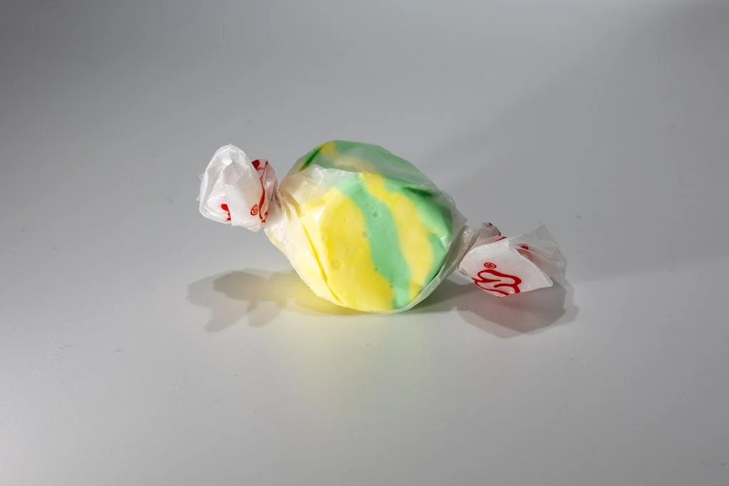 Yellow and green pineapple saltwater taffy from Sea Bird Gifts & Candy in Westport WA. Swirled tropical colors wrapped in wax paper with red print.