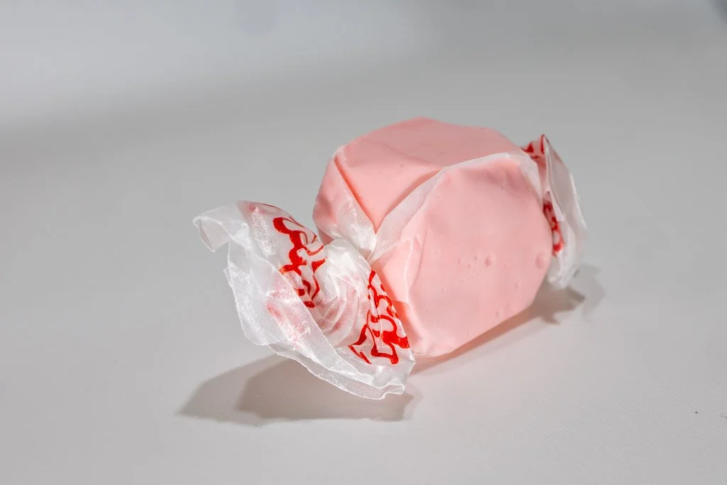 Bubble gum flavored taffy with clear wrapper with red lettering on the end. A soft pink piece of taffy.