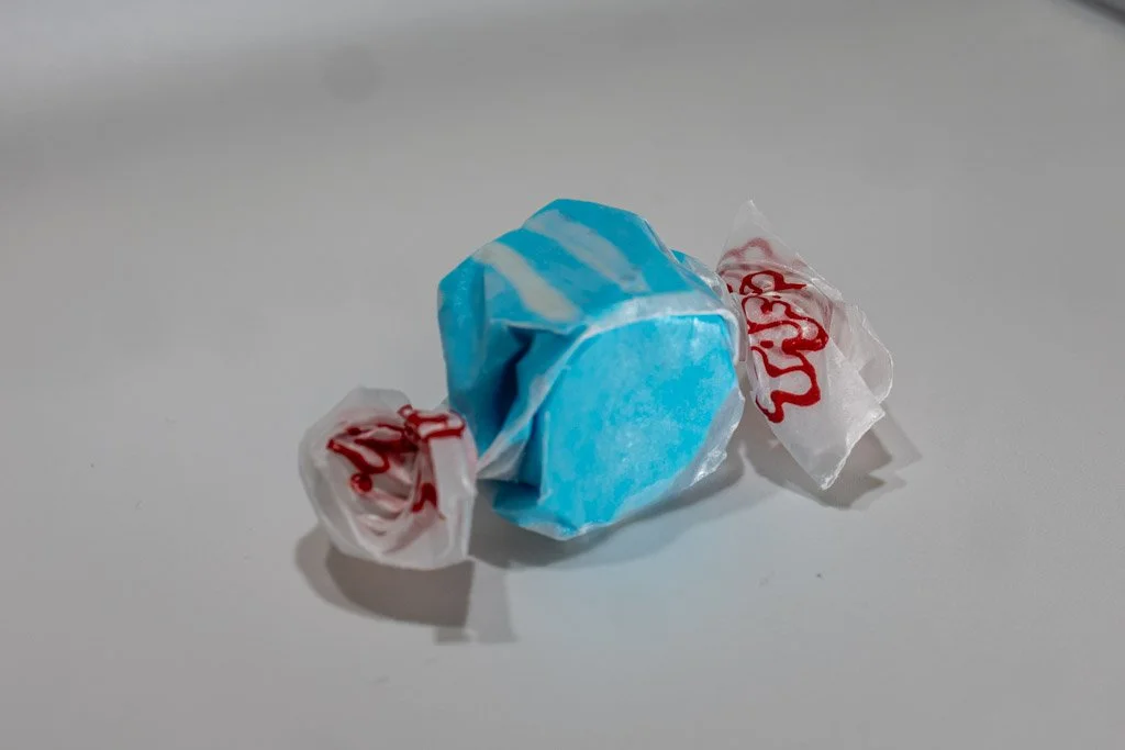 Blueberry flavored taffy in clear wrapper with red lettering on the ends. bright blue taffy with small white stripes on the outside.