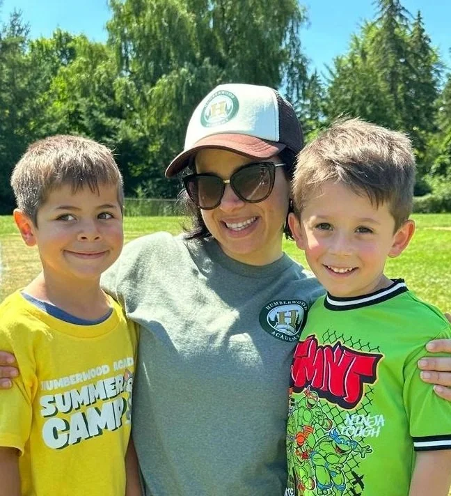 Teacher smiling and holding a paper, engaging with students in a classroom setting.