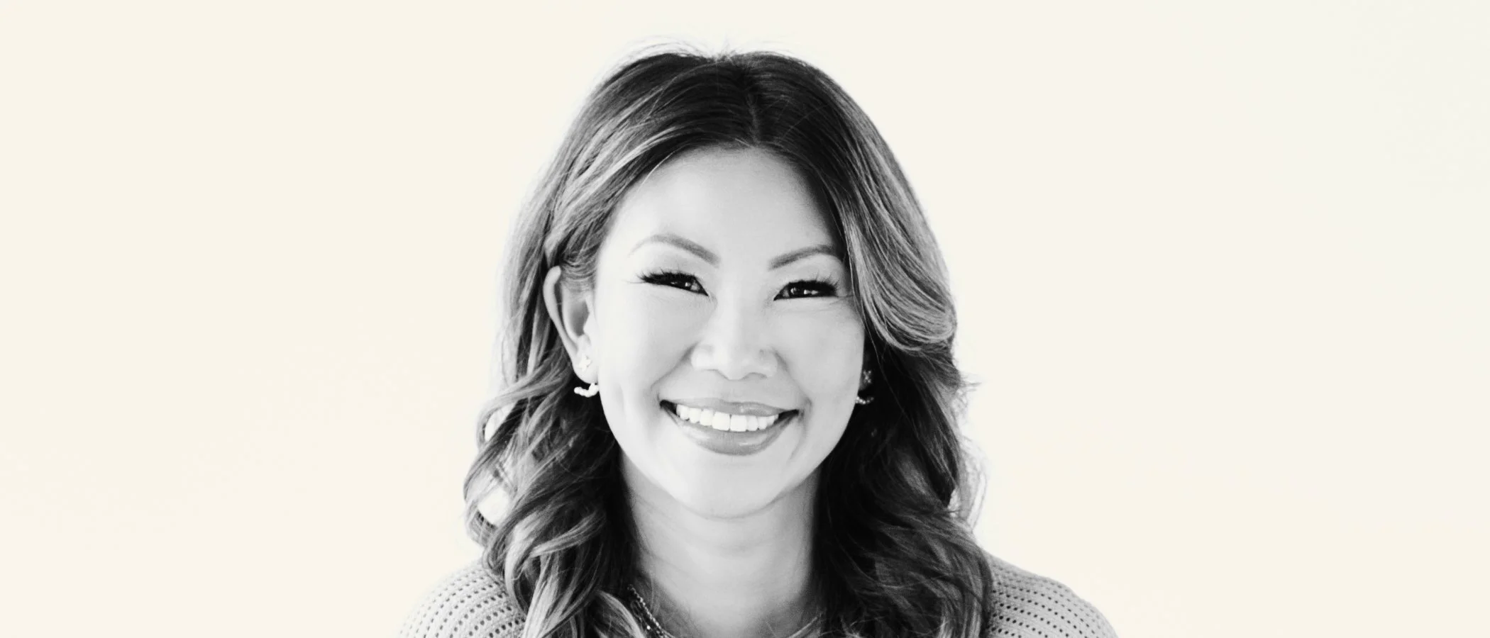 Smiling woman with wavy hair in a black and white portrait.