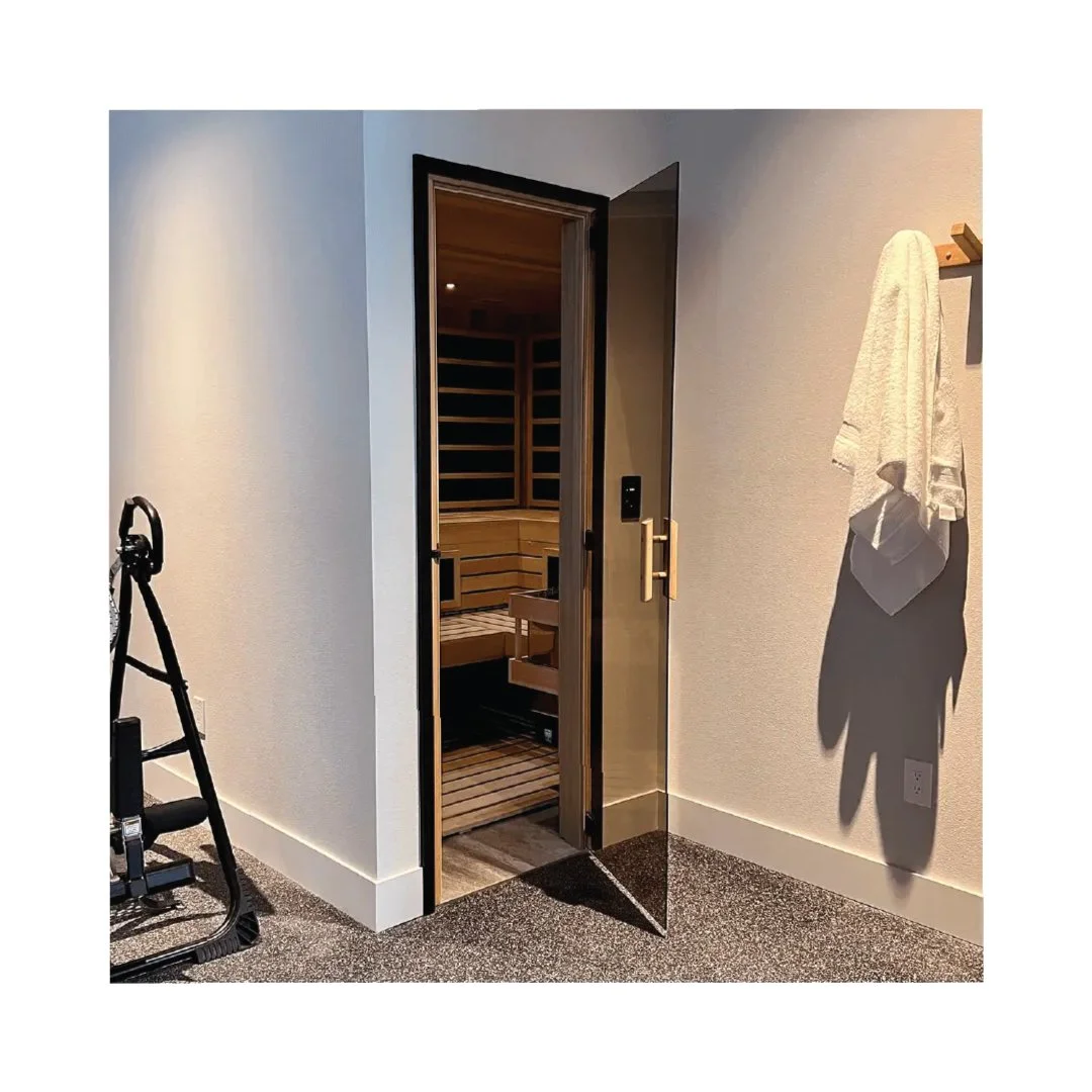 Room with open sauna door, exercise equipment, and towel on wall hook.