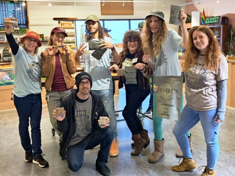 Sespe Creek Budtenders hold up Henry's Original Organic Sungrown Cannabis Products while wearing swag shirts illustrated by Taylor T. W. Rushing