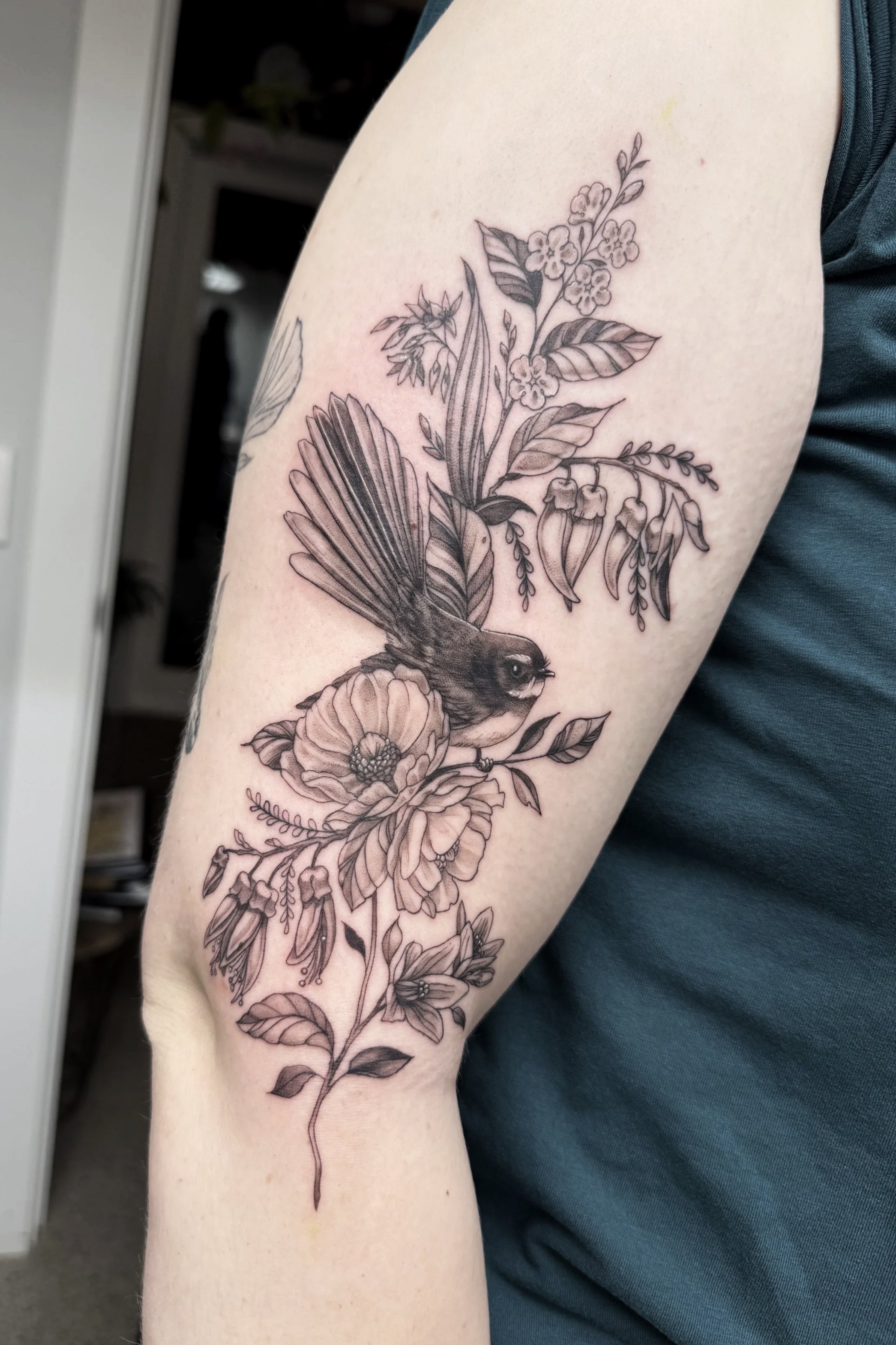 Fine line Rolla tattoo fantail native New Zealand bird with flowers, soft and feminine done in Frankton, Queenstown