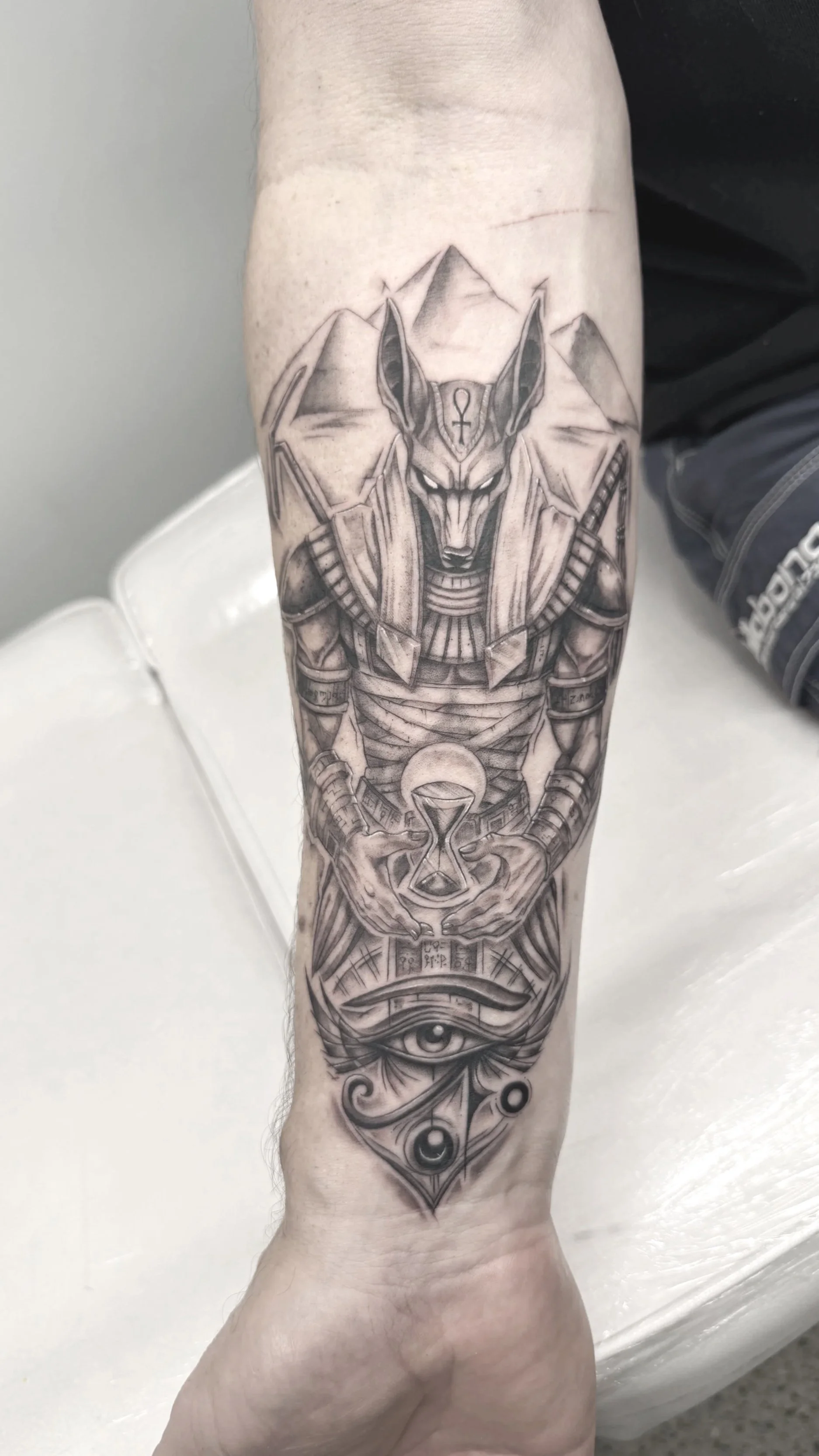 Egyptian god Anubis and eye pyramids on arm tattoo