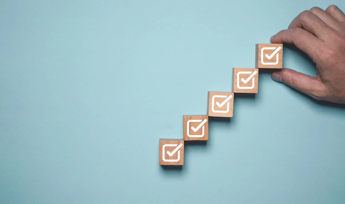 A series of wood blocks with white check marks arranged to look like an ascending staircase.