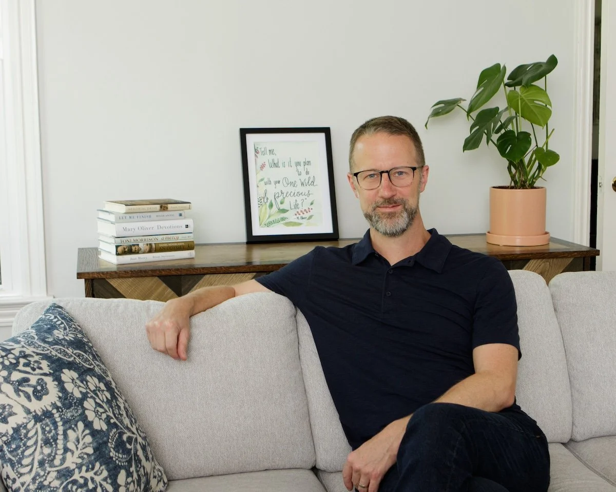 Chris Copeland sits on a couch with one arm draped over the back.
