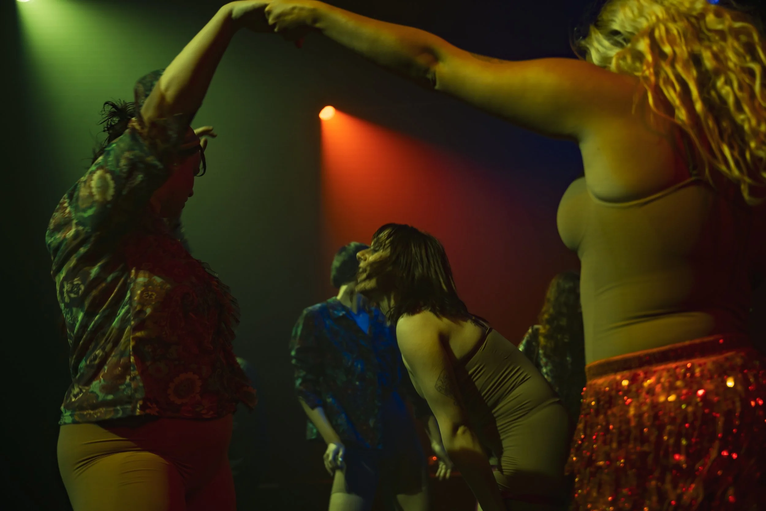 People dancing in a dimly lit nightclub with colorful lighting.