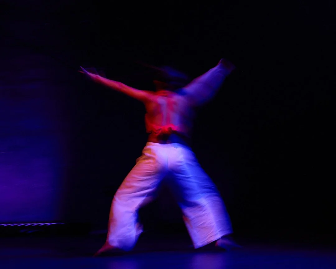 A person dancing on stage under colored lights in motion blur
