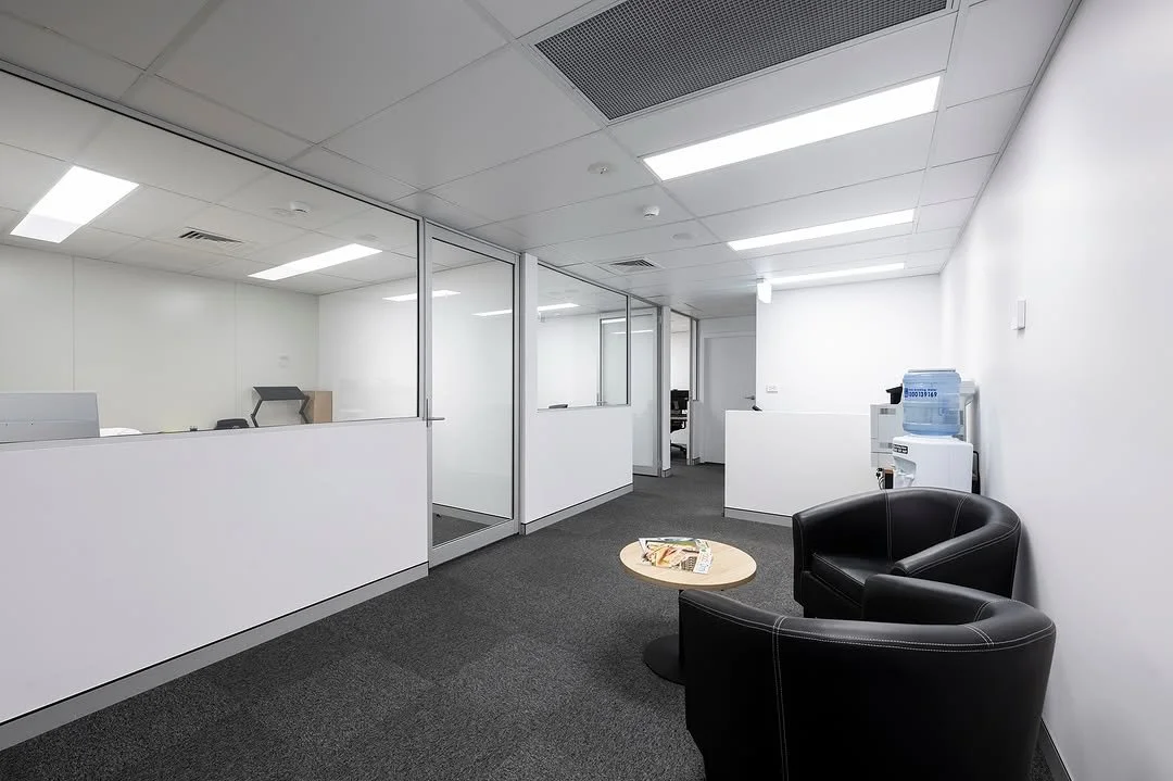 Modern office reception area with black chairs and water cooler.