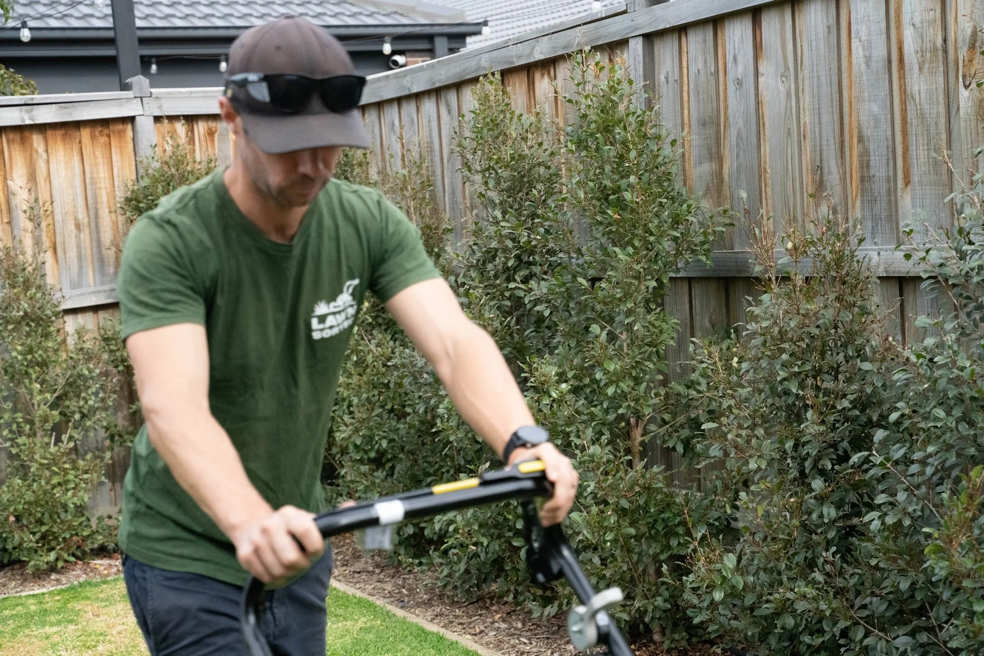 Lawn Sorted crew member in a green Lawn Sorted shirt pushing a lawn mower