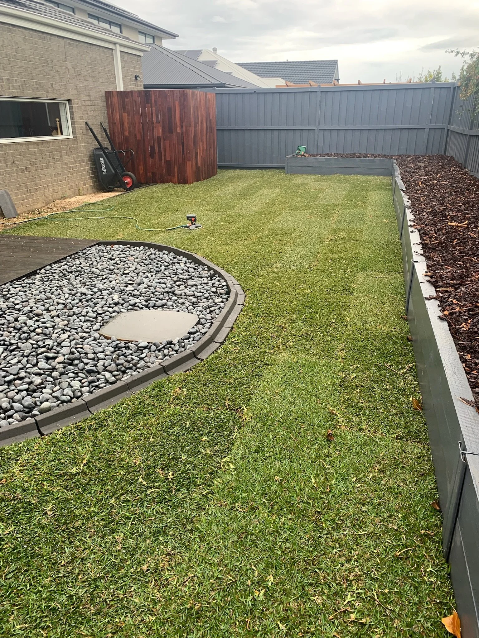 Completed turf installation in a Geelong backyard by Lawn Sorted — fresh lawn with pebble garden feature and raised garden beds