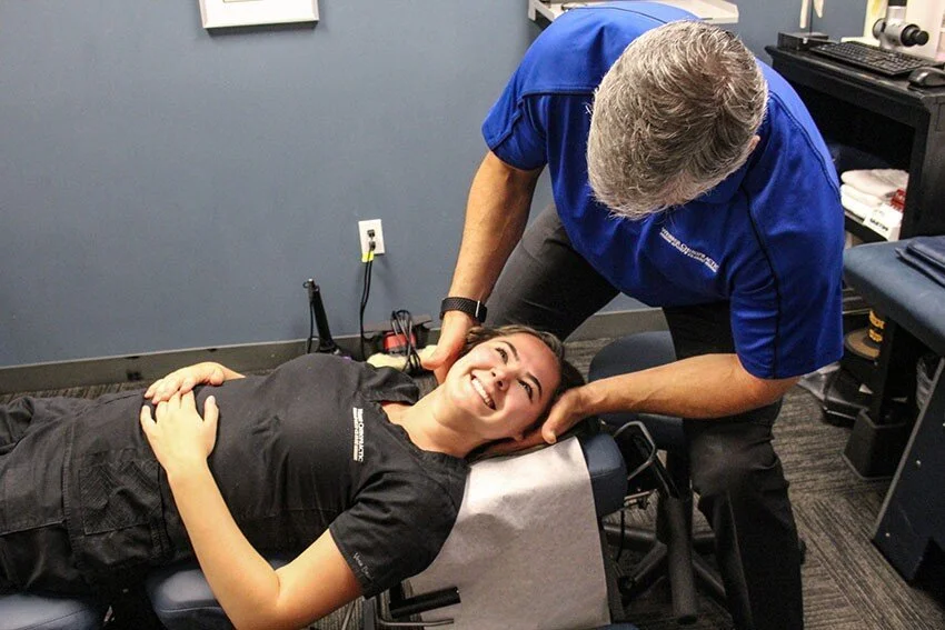Dr. Mark Webber, chiropractor, performing an adjustment on a smiling woman lying on a treatment table at the Kirkland, WA clinic.
