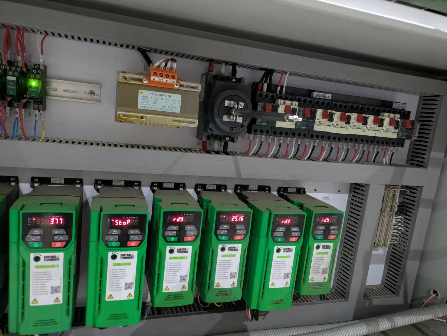 Electrical control panel with circuit breakers, relays, digital controllers, and wiring.