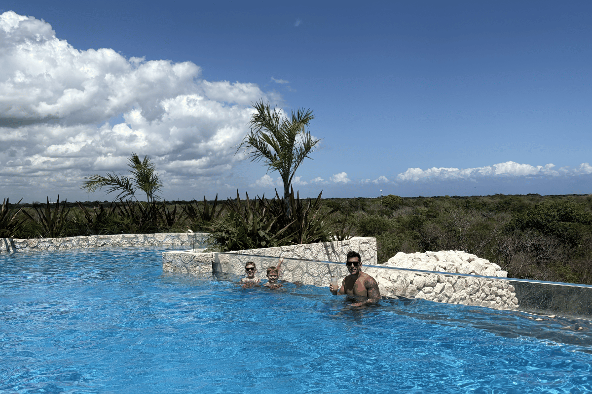 Heated rooftop infinity pool at Hotel Xcaret Mexico with family enjoying pool and jungle views