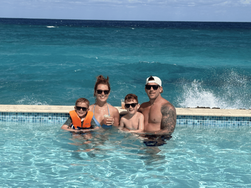 Family enjoying heated pool at Royal Beach Club Nassau with ocean waves in background