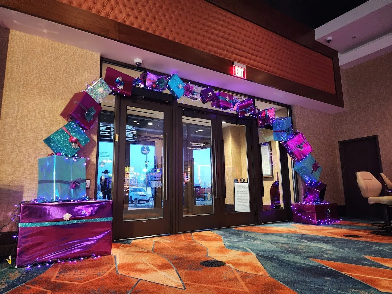 Decorative arch made of colorful gift boxes and string lights at the entrance of a building.
