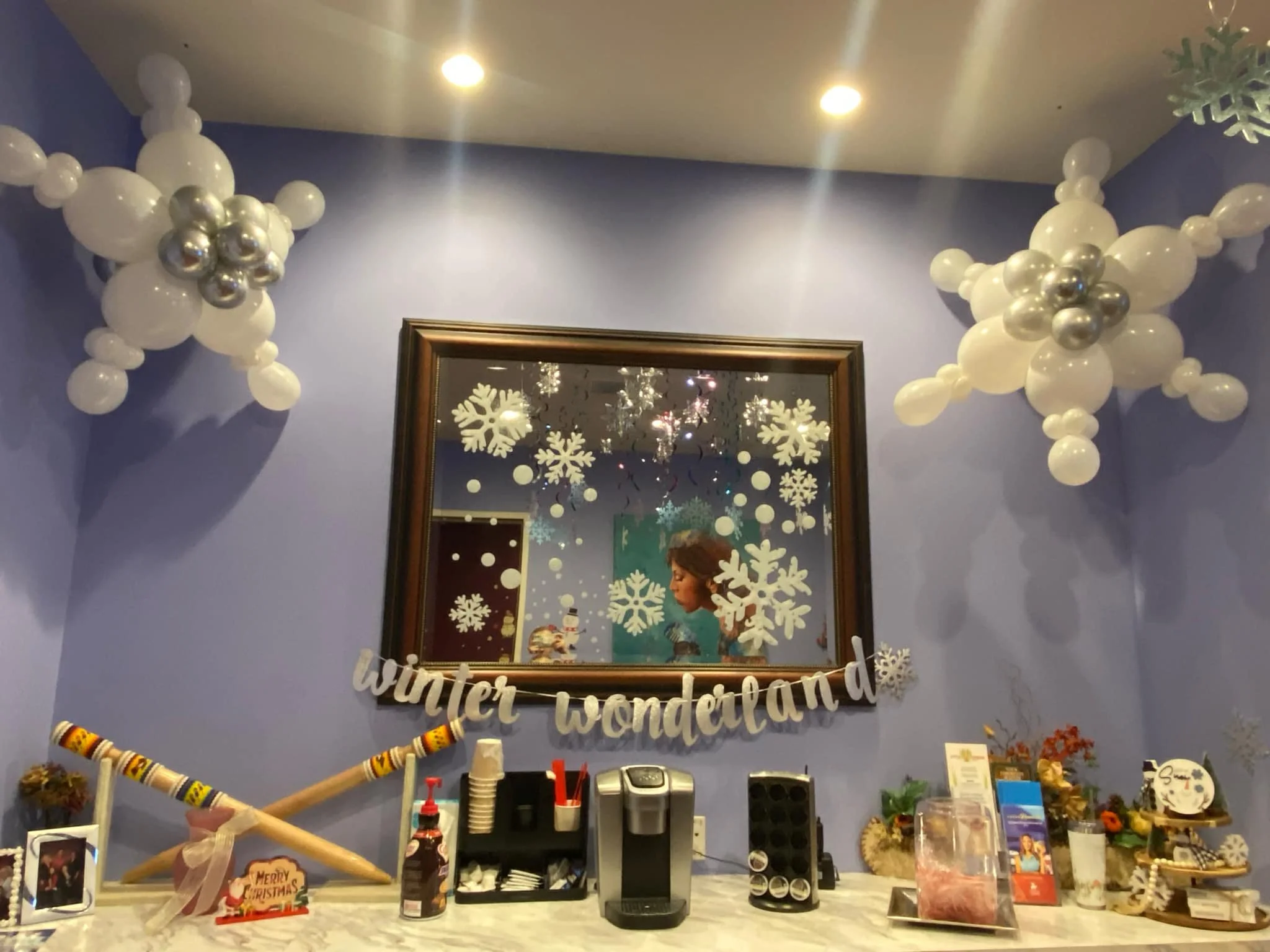 Decorated indoor space with winter and holiday themed balloons, snowflake window decals, and a 