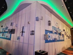 Blank white wall with blue and black 'Coming Soon' signs, part of a food court area.