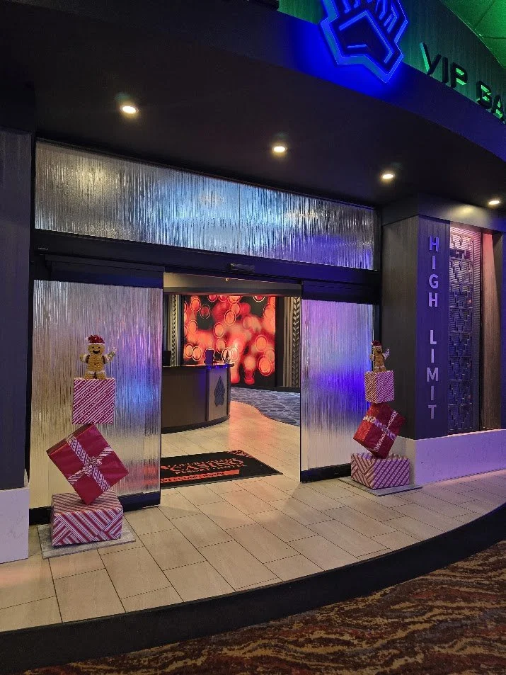 Hotel entrance decorated with Christmas holiday decor, including stacked gift boxes and holiday figures, with a fuzzy red and green digital display in the background.