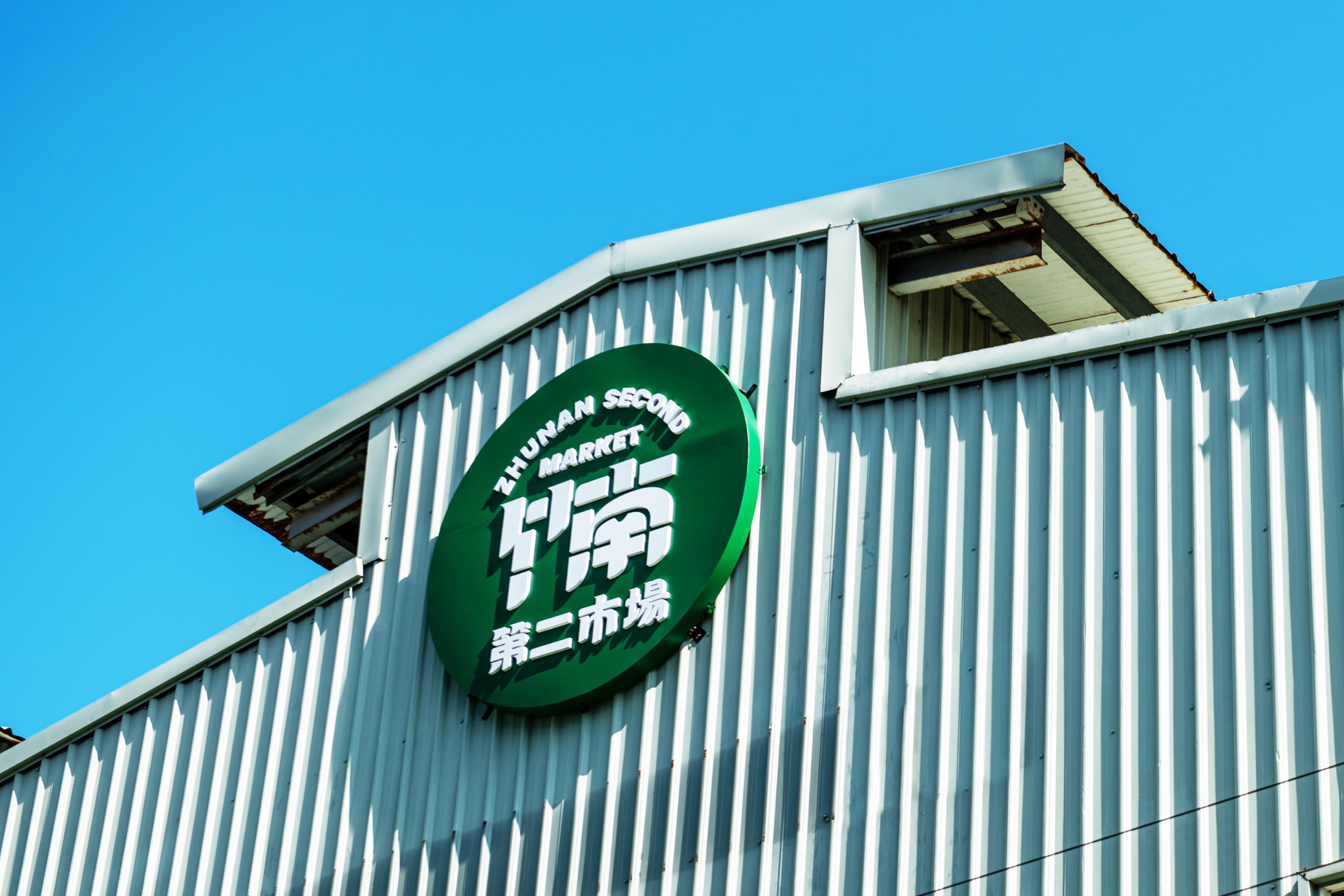 Exterior view of Zhunan Second Market building with a green sign against a clear blue sky.