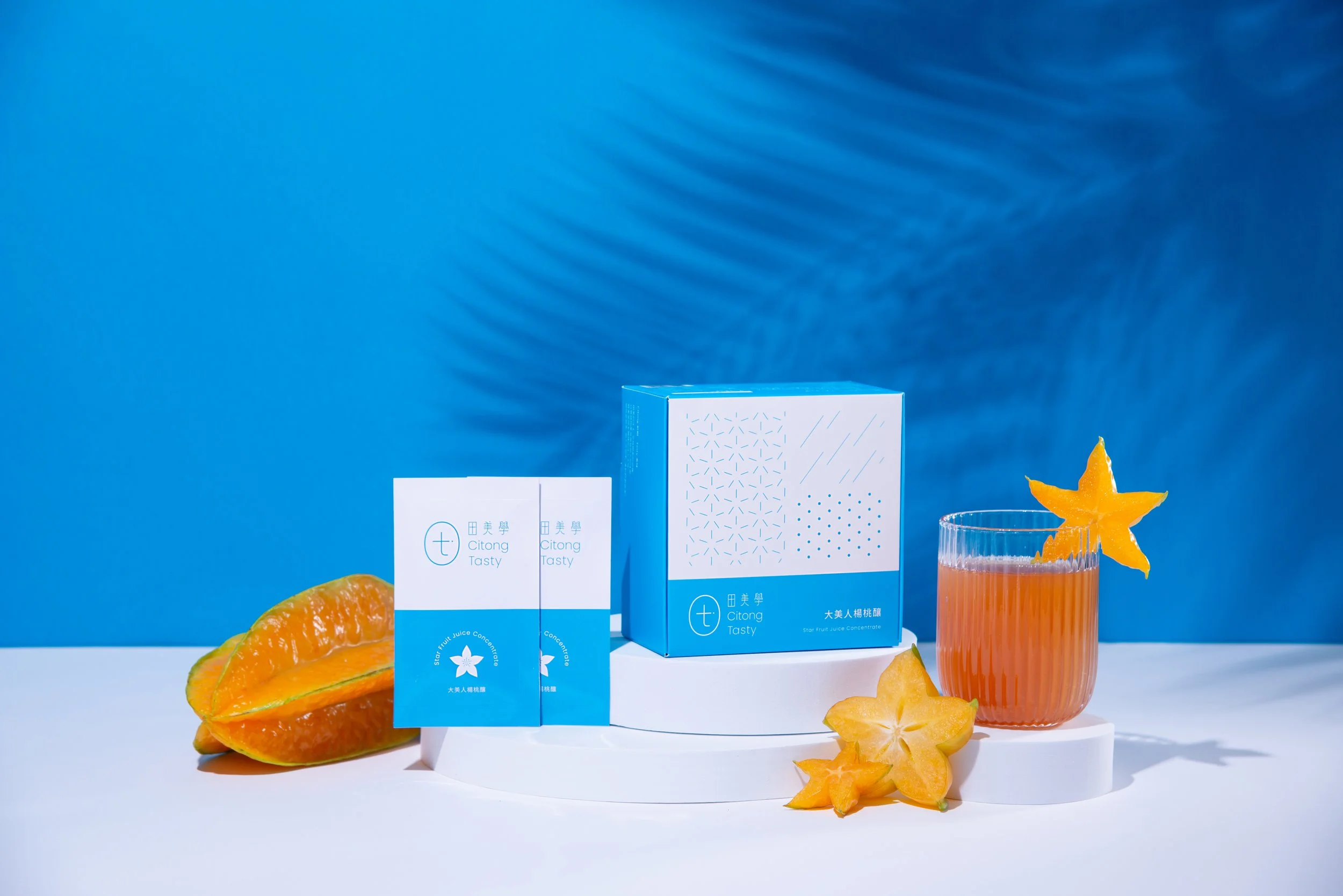 A product display featuring a box of Citong Tasty star fruit juice concentrate, with star fruit slices and a glass of star fruit juice on a white surface against a blue background.