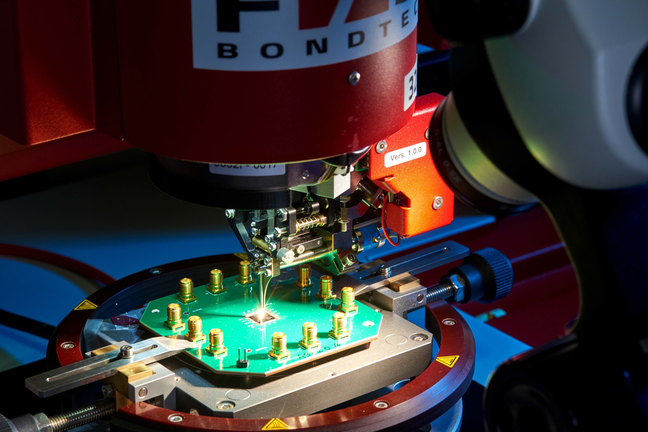 Close-up of a scientific laser system performing on a green circuit board with gold components, under a specialized microscope