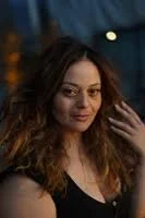 Woman with long hair in dim lighting, smiling slightly at the camera.