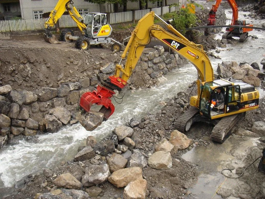 Construction site with excavators working in a river, removing rocks and earth for infrastructure development.