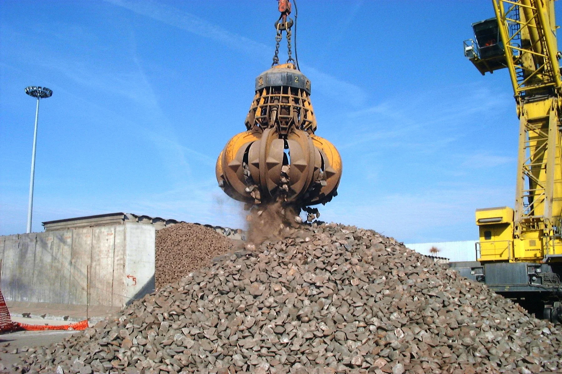 Close-up of a Rozzi Electro hydraulic orange peel grab unloading and loading stone into ships on a port. 
