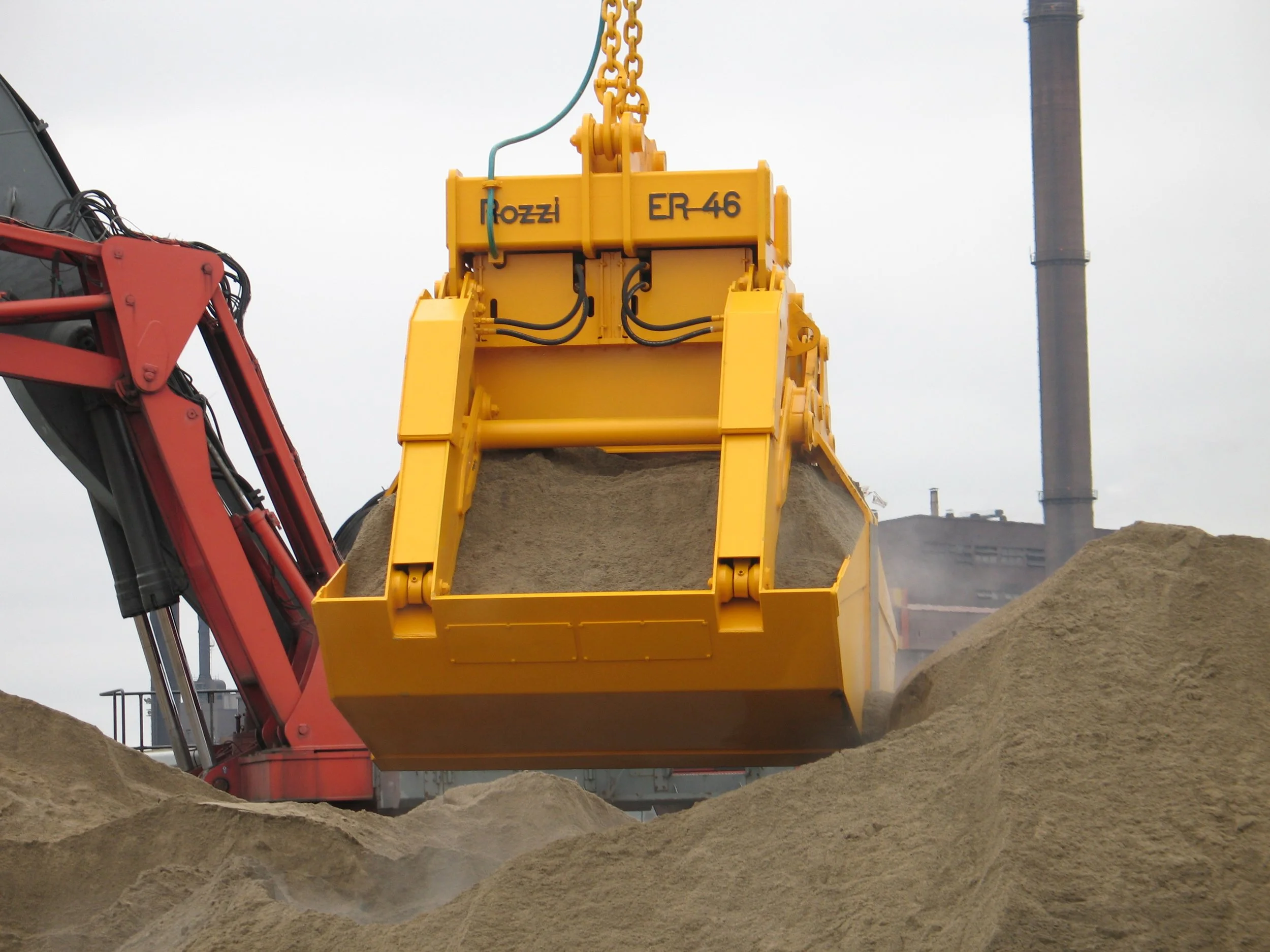 Close-up of a Rozzi Electro hydraulic Clamshell grab unloading sand in a port.