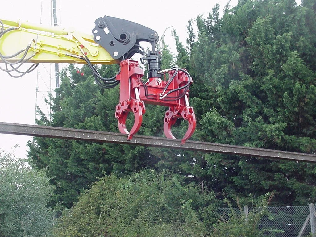 A machine with hydraulic railway sleeper claw attachment gripping a rail beam.