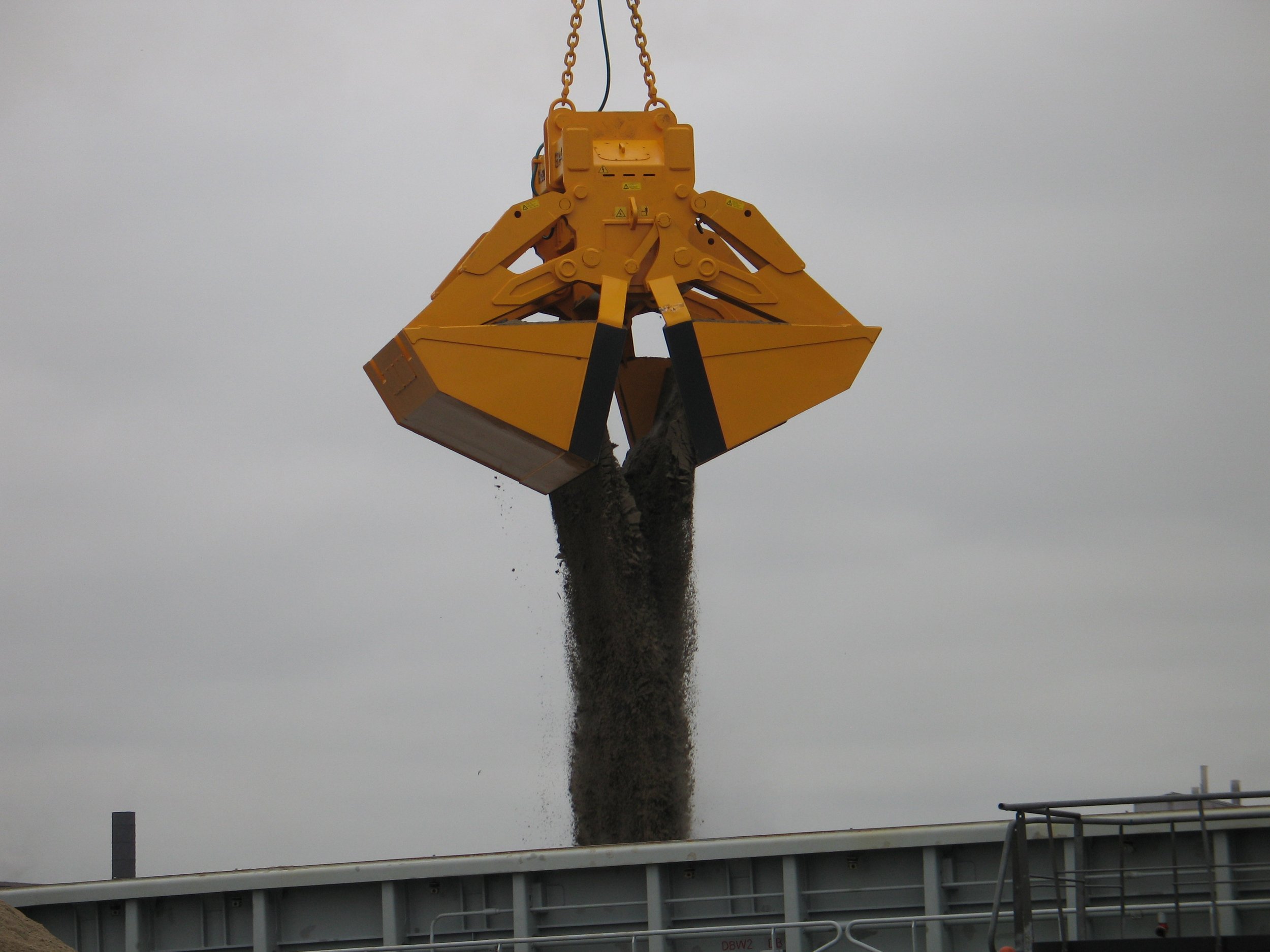 	
Close-up of a Rozzi Electro hydraulic Clamshell grab unloading sand in a port.