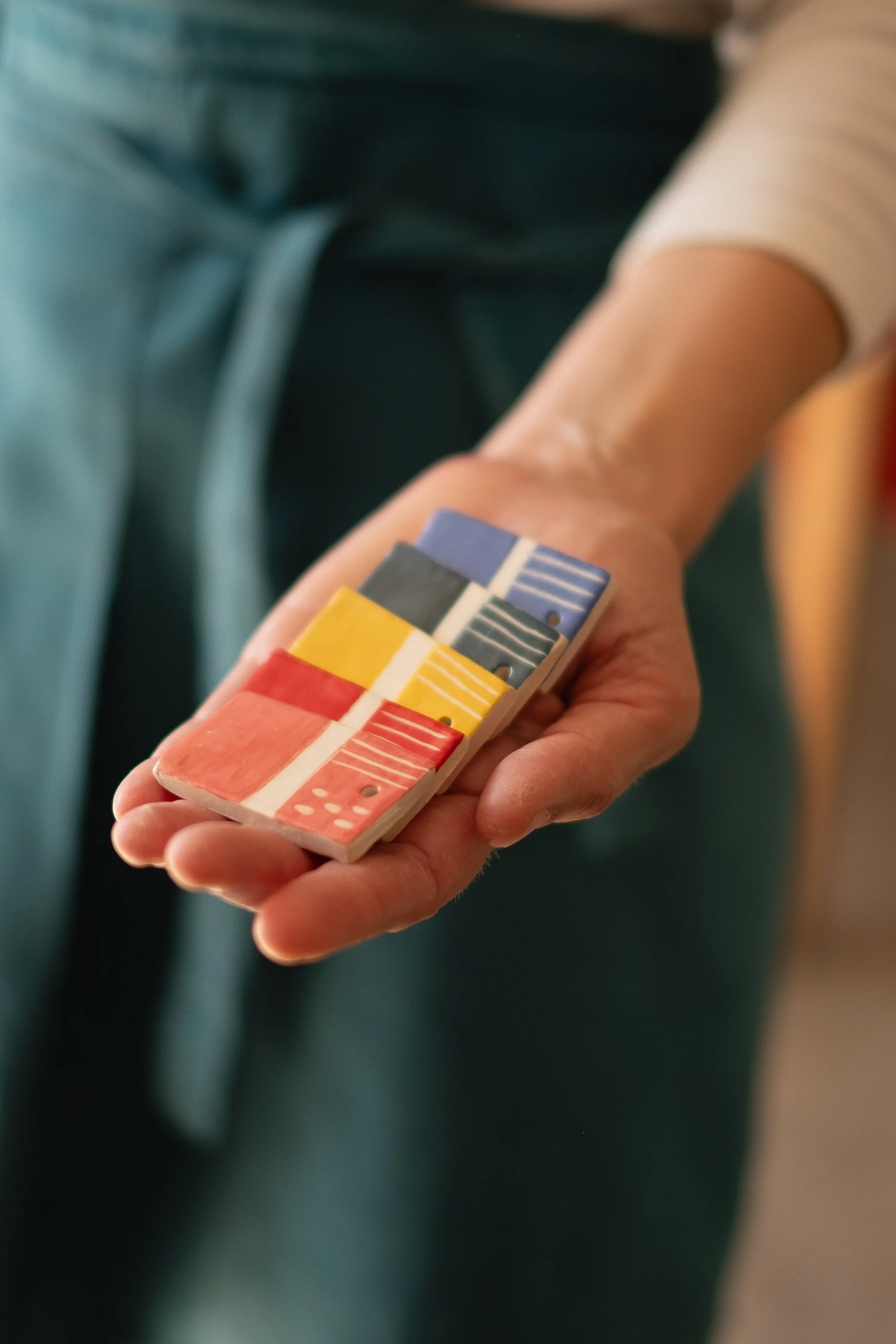 La mano di un'artigiana che tiene un set di campioni di piastrelle in ceramica. 