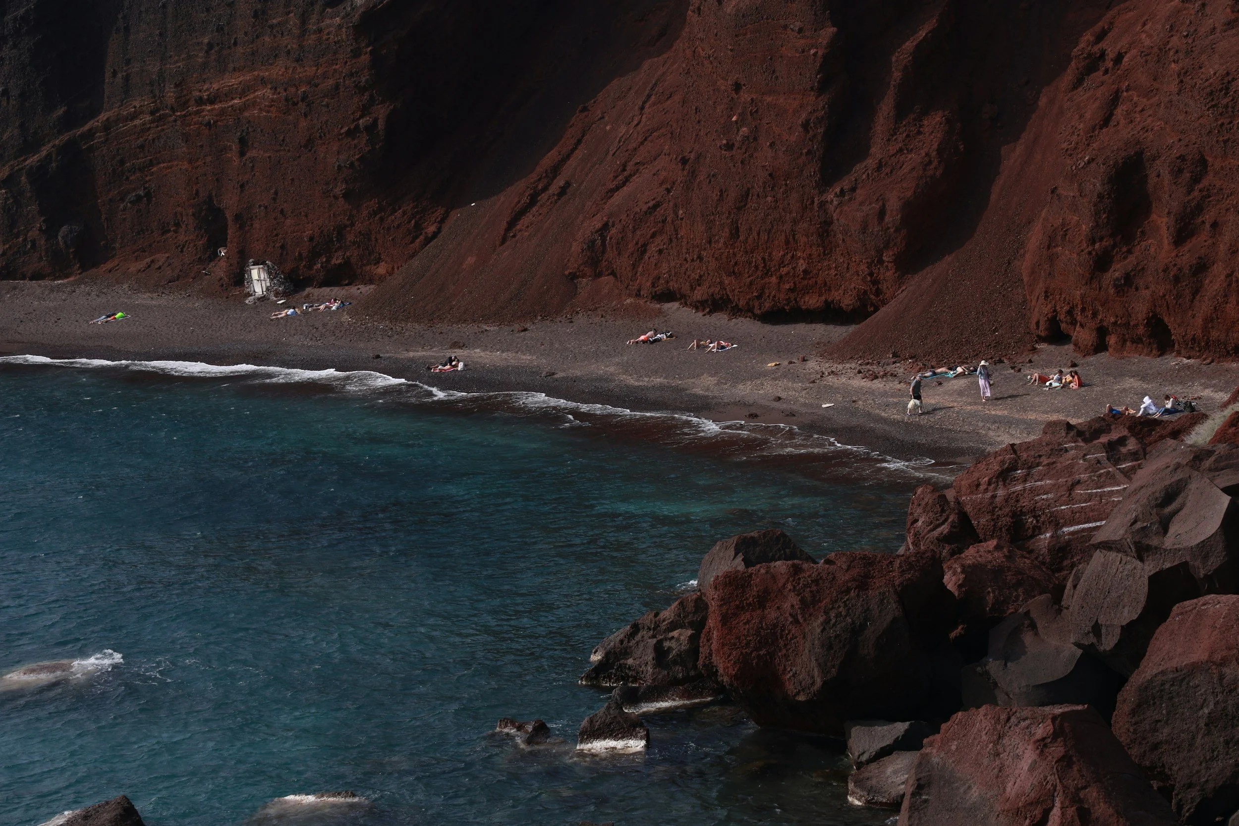 Santorini volcanic coastline with Red Beach during morning catamaran cruise