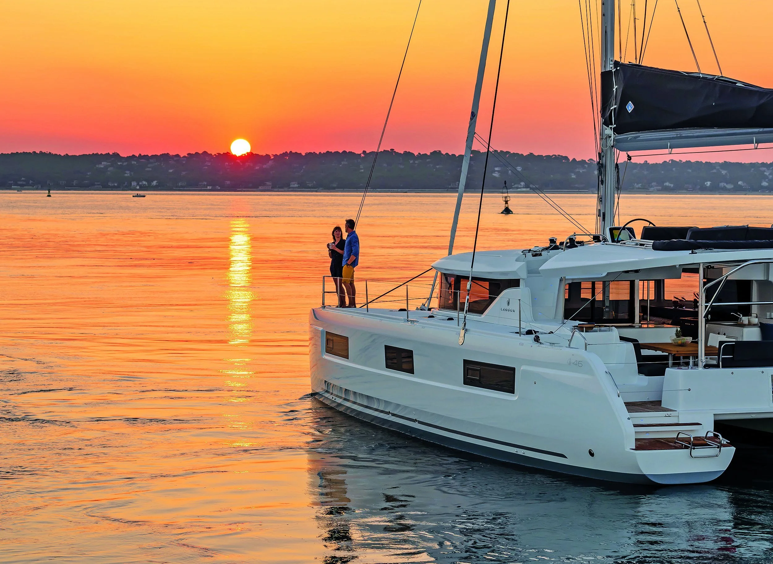 Catamaran sailing at sunset along Santorini coastline