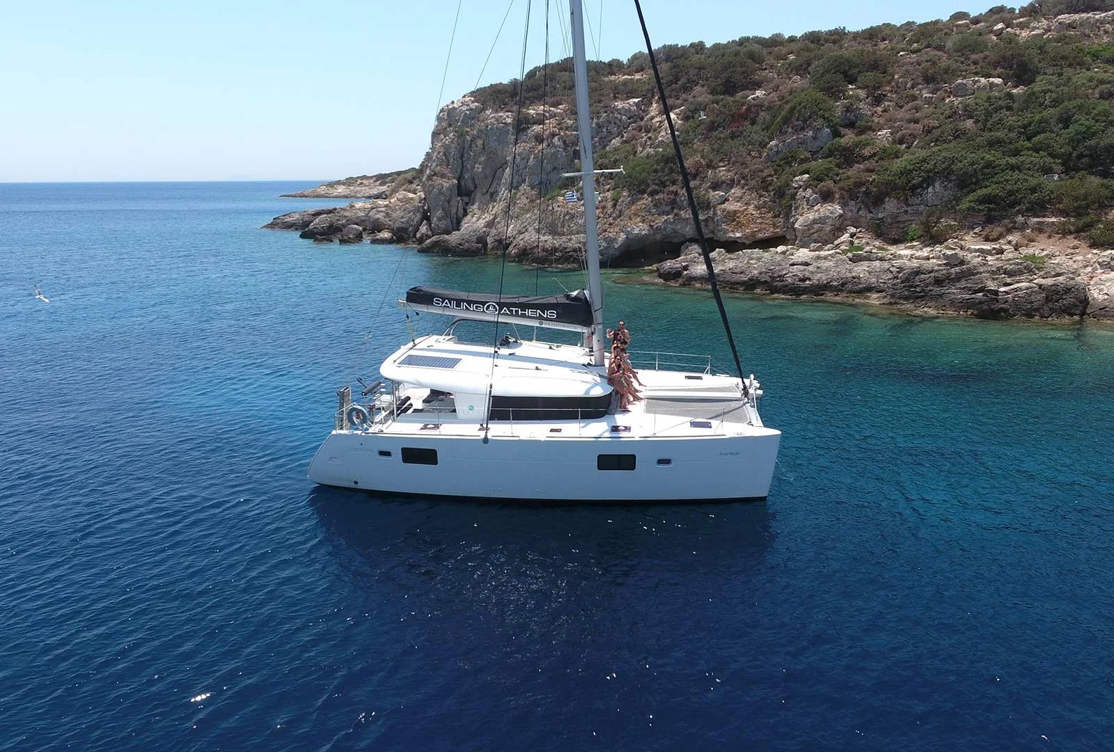 Catamaran sailing along the Athens Riviera coastline near clear blue waters