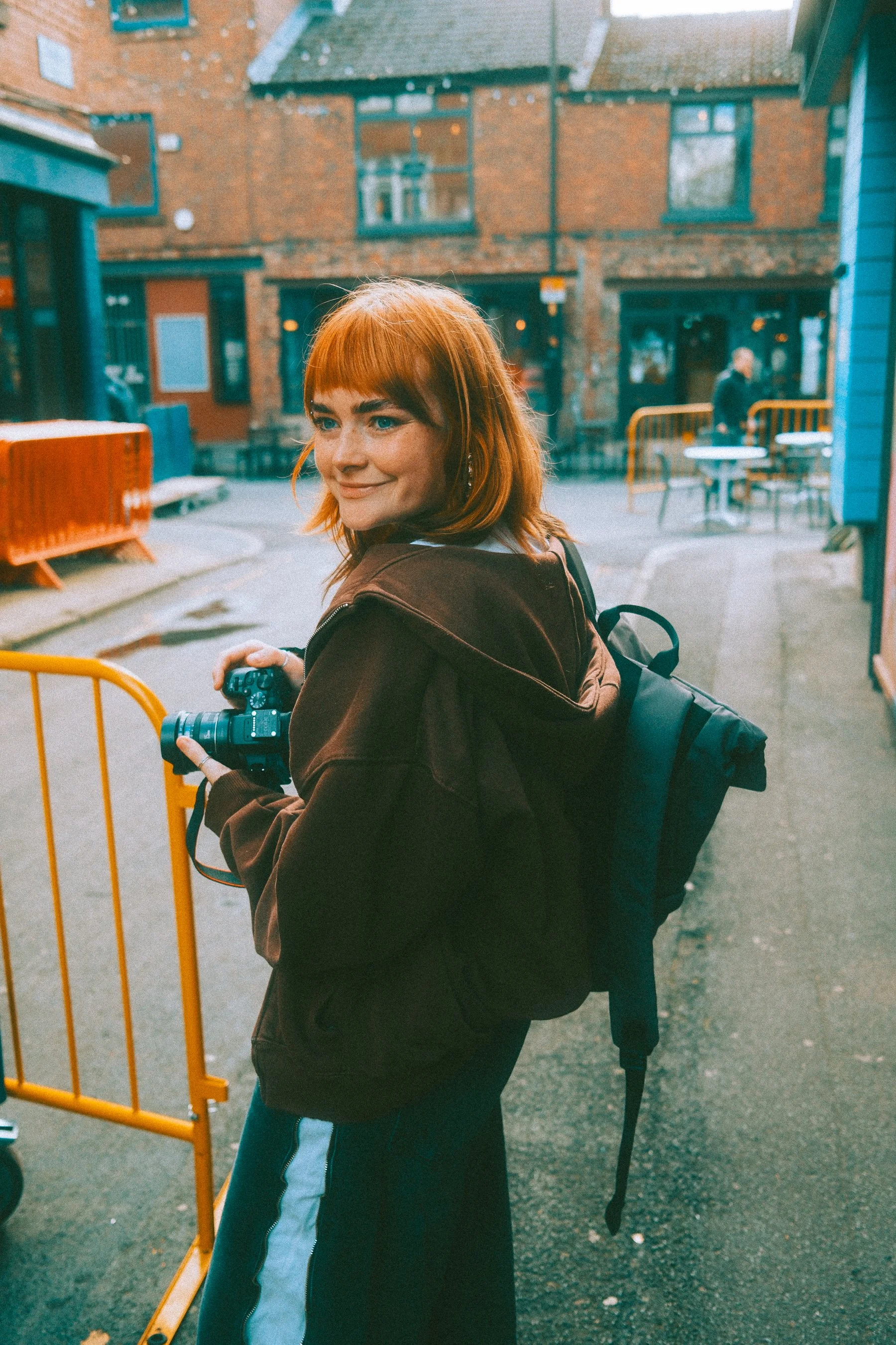 Anna Goley holding a camera smiling into the distance