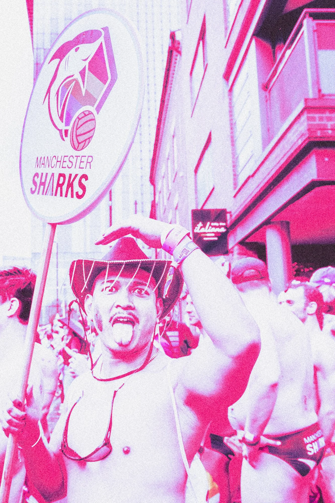 A person at a sports event holding a Manchester Sharks banner, with other spectators in the background.