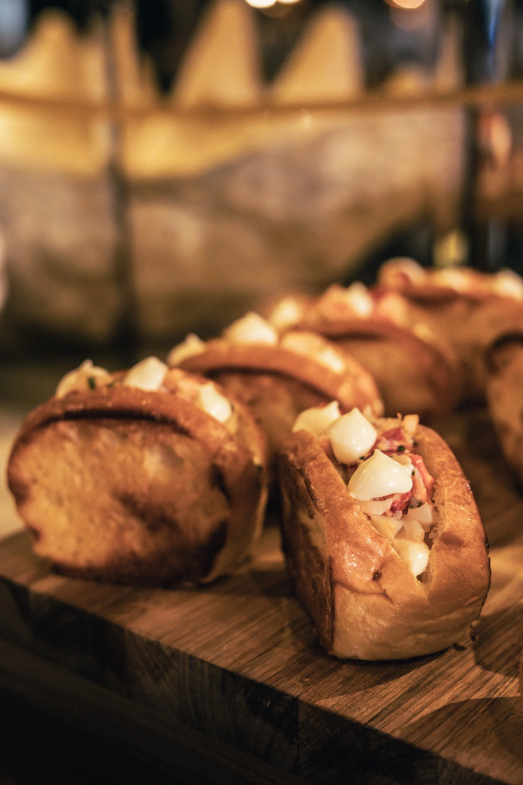 Close-up of stuffed bread rolls filled with meat and topped with diced onions on a wooden board.