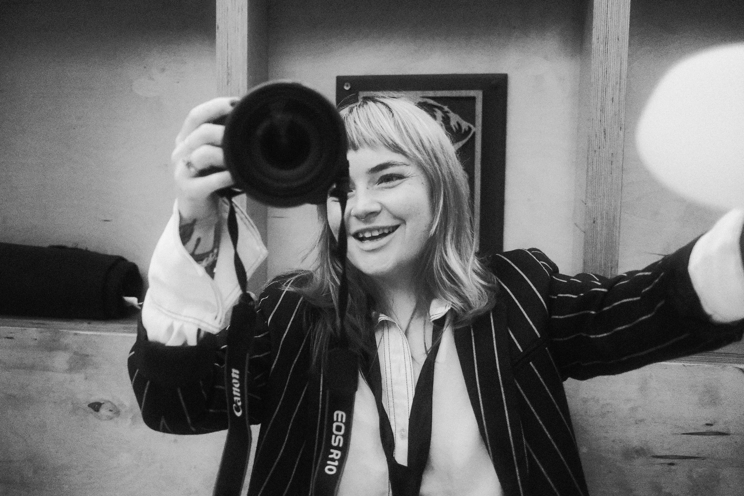 A person holding a camera up with a happy expression on their face