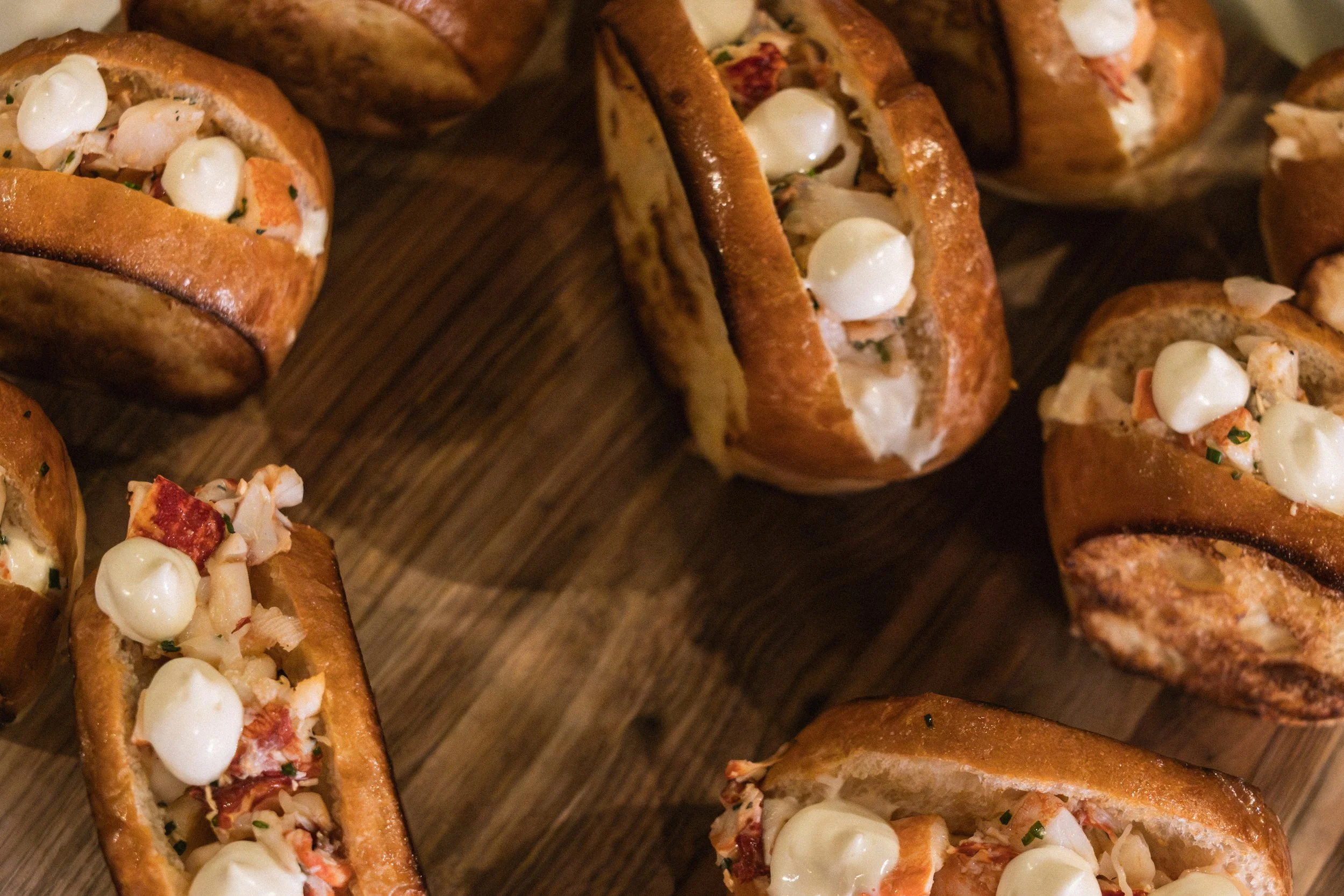 Close-up view of mini lobster rolls with lobster meat, mayonnaise, and herbs served on toasted bread.