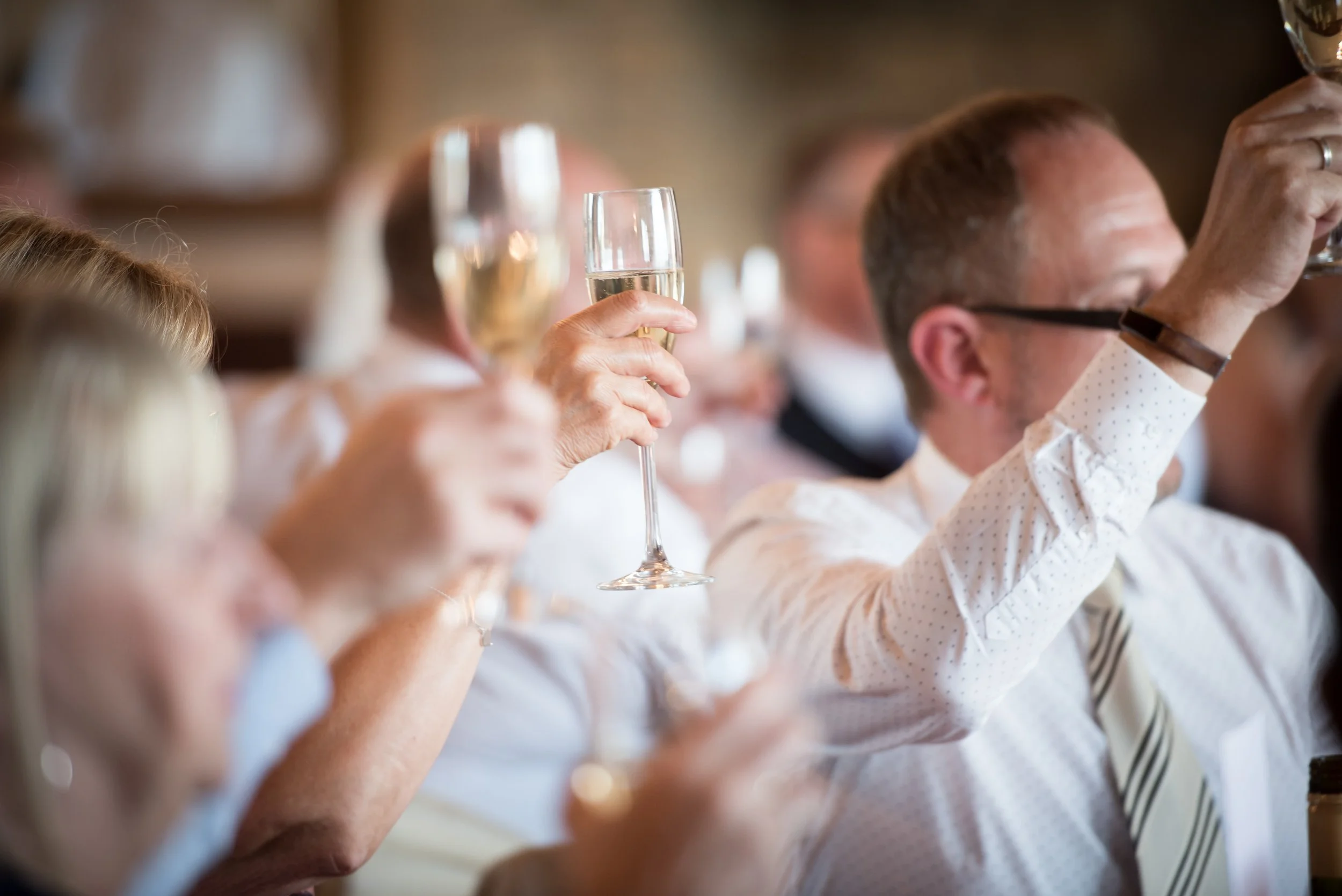 People attending a celebration raising glasses of champagne for a toast.