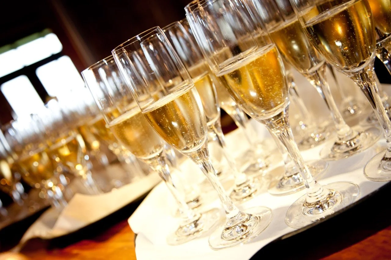 Multiple glasses of champagne on a tray at a celebration or event.