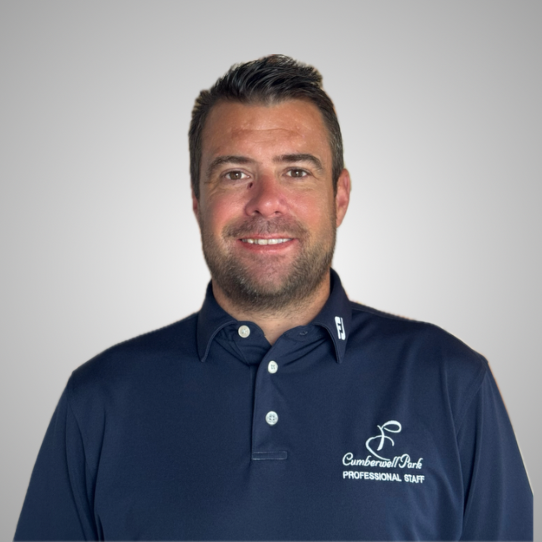 Headshot of a man with dark hair and beard, wearing a navy blue collared polo shirt with logo and text, smiling, against a plain light gray background.