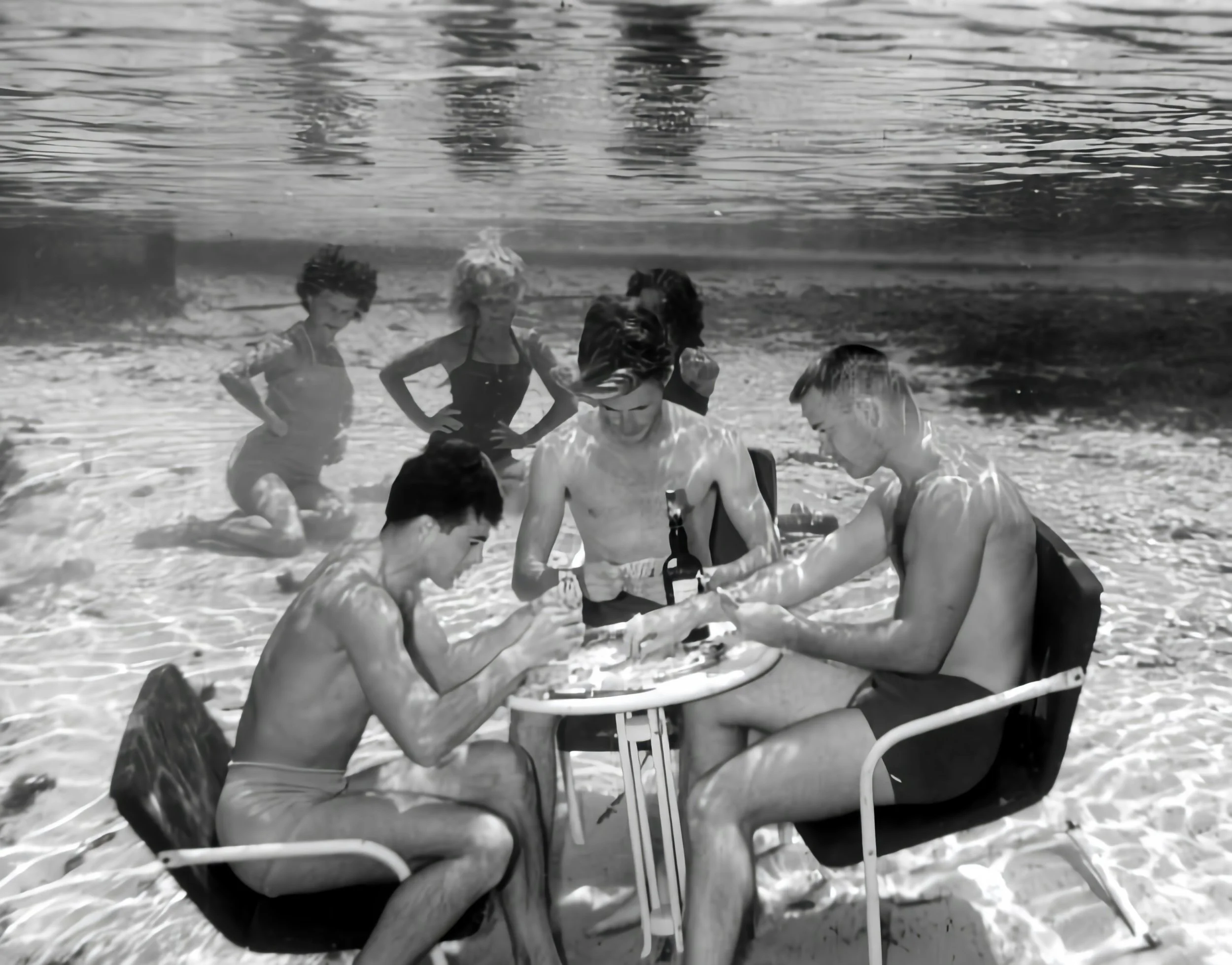 Gruppen von Jugendlichen sitzen in Liegestühlen am Strand und genießen die Sonne.