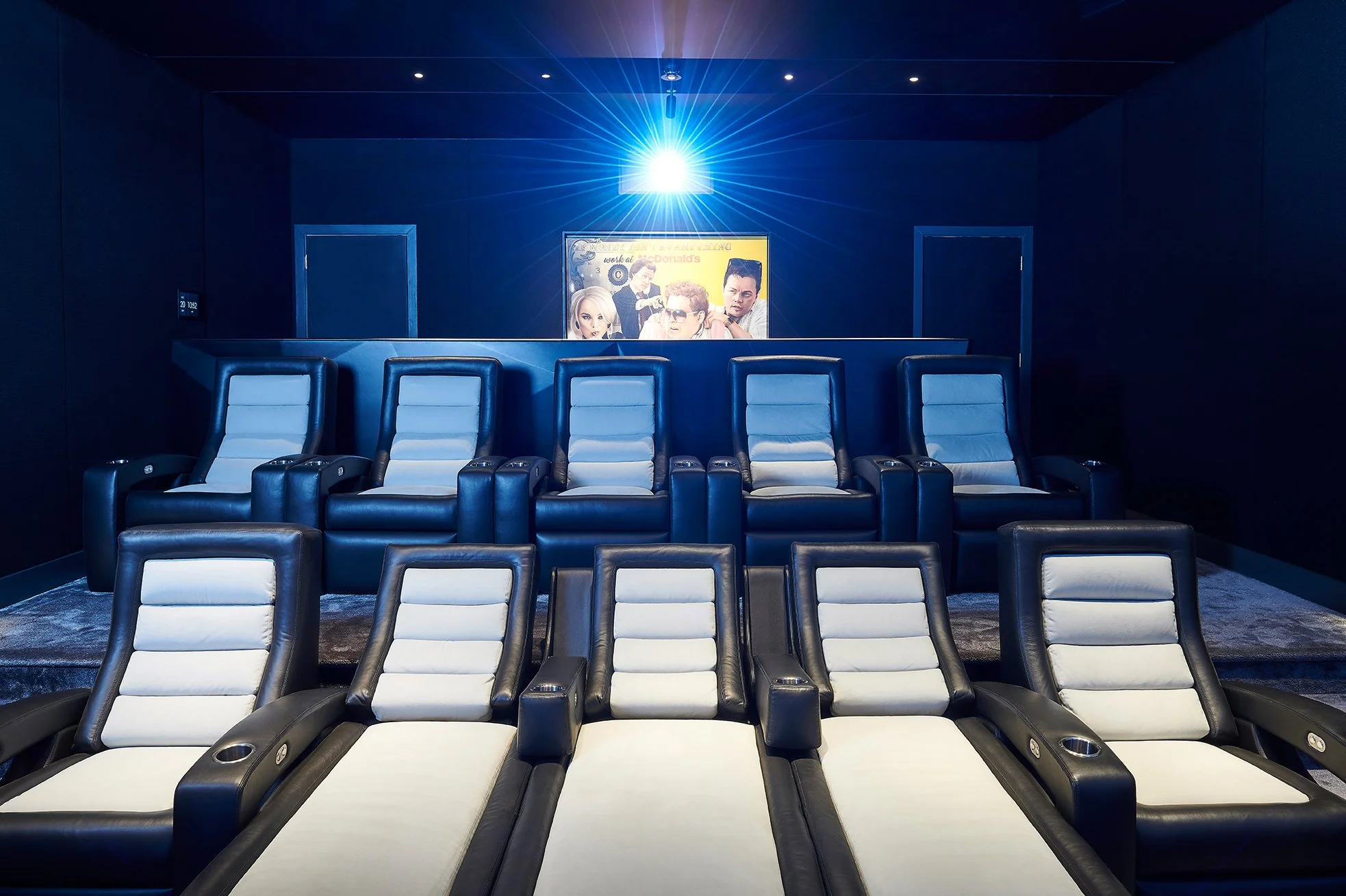 Luxury home theater with leather recliners, projector, and movie poster on wall.
