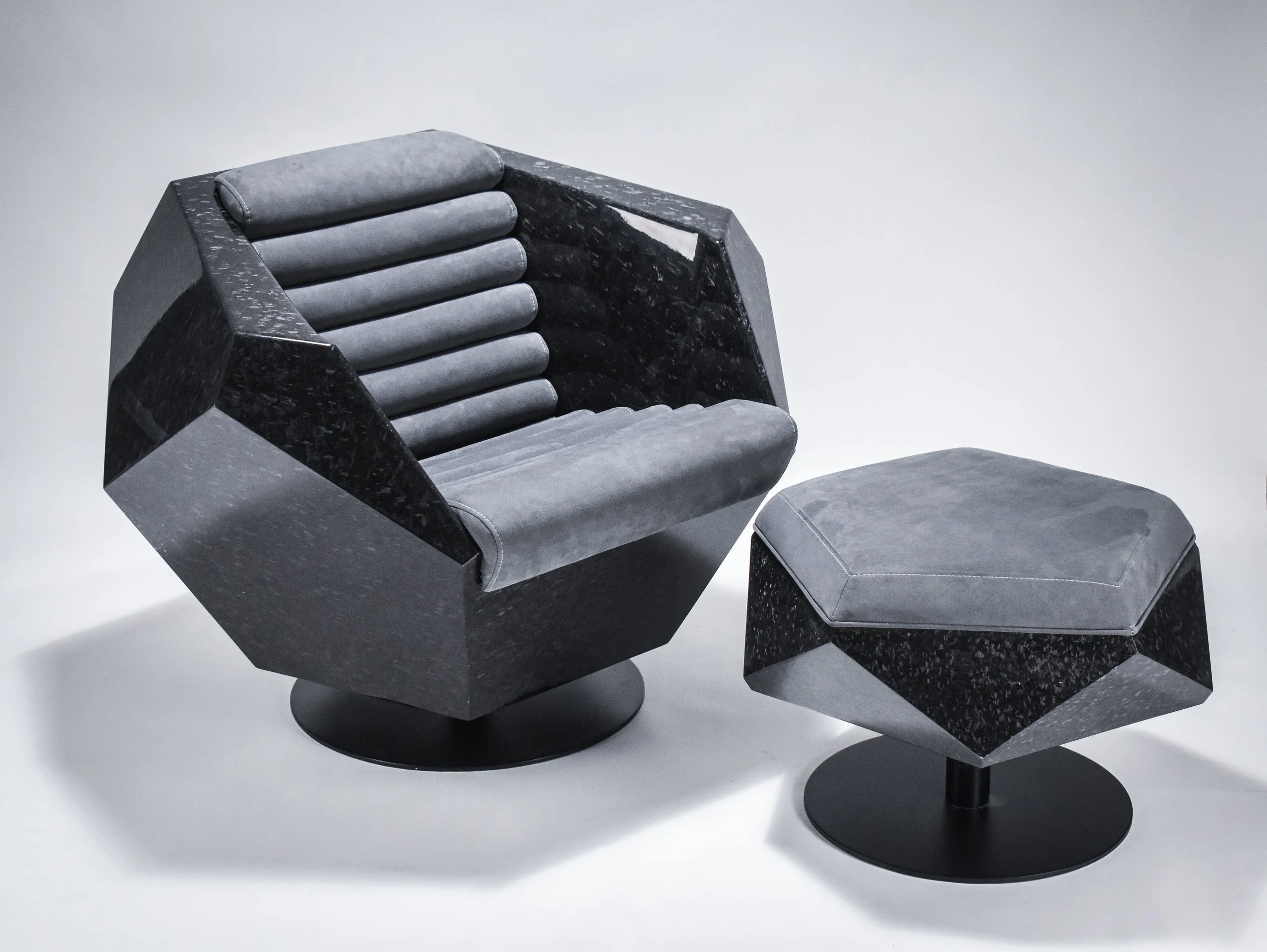 Geometric black chair with gray cushion and matching ottoman on a pedestal base.
