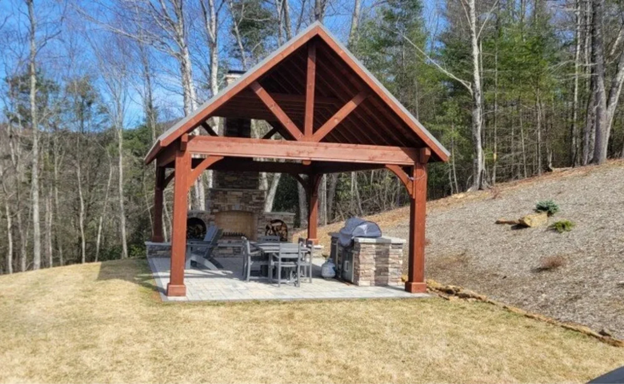 Luxury outdoor kitchen with stone patio, built-in grill, seating area, and landscape lighting