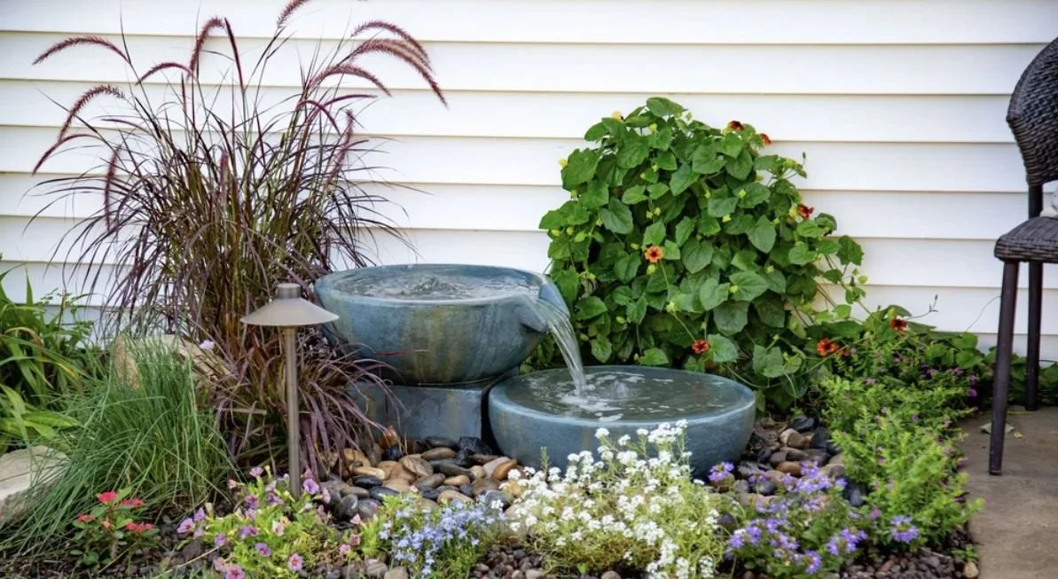 Backyard aquascape with natural stone waterfall and pond surrounded by landscaping in North Carolina